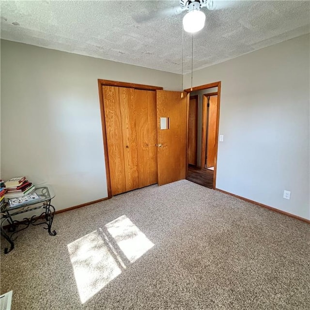 unfurnished bedroom featuring carpet floors, ceiling fan, baseboards, and a textured ceiling