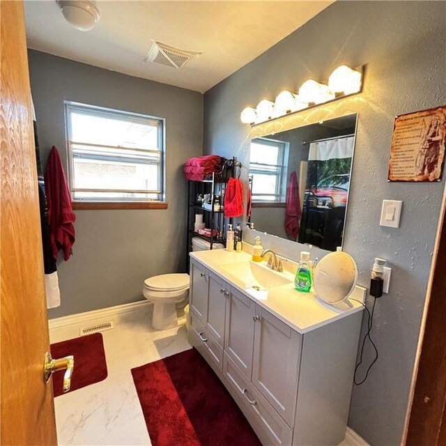 full bath with toilet, vanity, visible vents, and baseboards