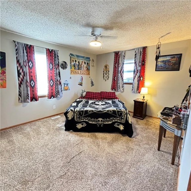 carpeted bedroom featuring a ceiling fan, multiple windows, baseboards, and a textured ceiling