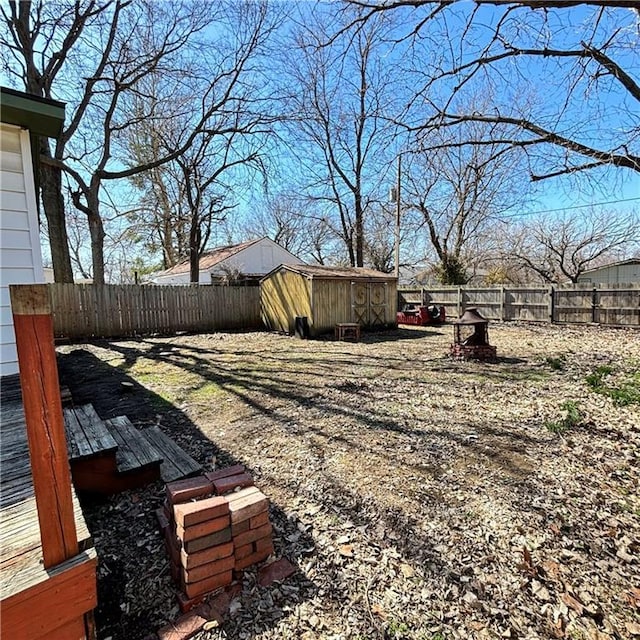 view of yard with an outbuilding, a fenced backyard, a deck, and a shed