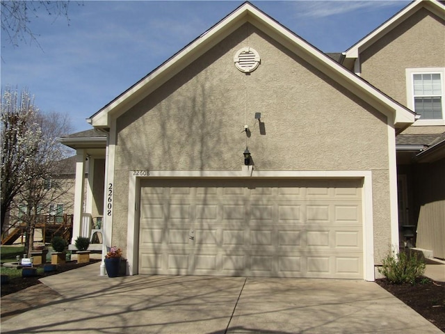 view of side of home with a garage, driveway, and stucco siding