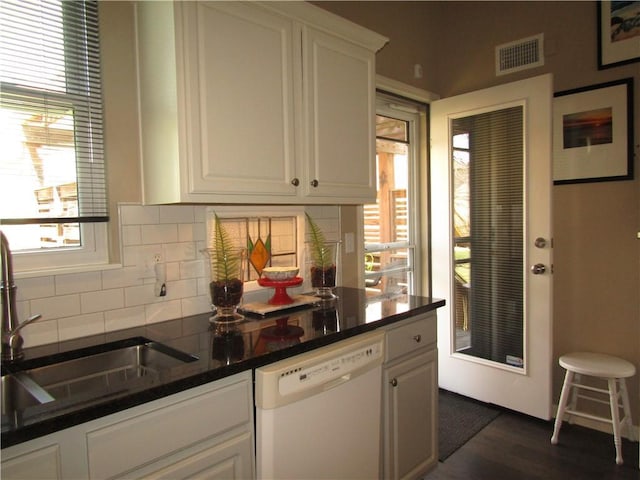 kitchen with white dishwasher, plenty of natural light, visible vents, and decorative backsplash