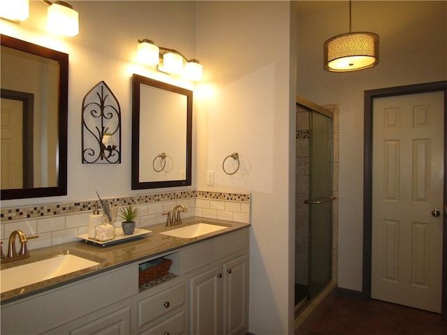 bathroom featuring double vanity, tasteful backsplash, a stall shower, and a sink