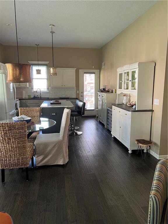 kitchen featuring white cabinets, tasteful backsplash, dark wood-style flooring, freestanding refrigerator, and a kitchen island