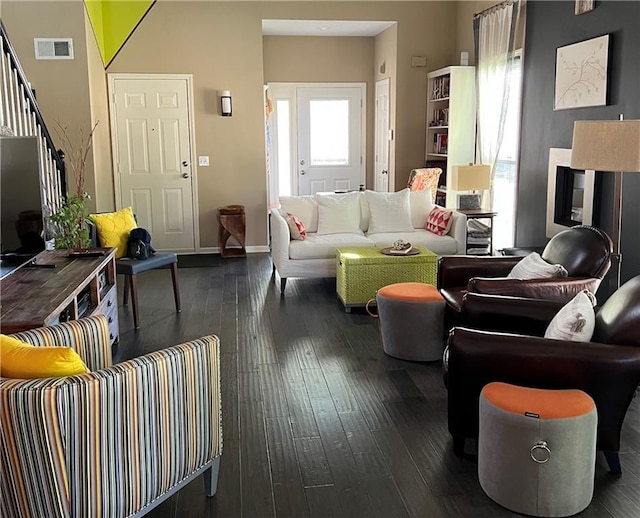 living area featuring baseboards, visible vents, stairs, and dark wood-style flooring