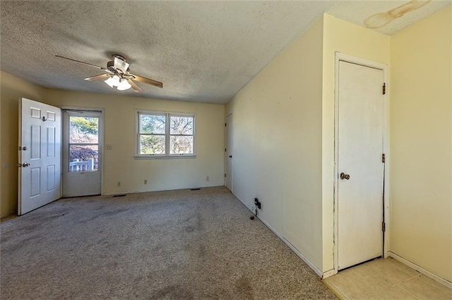 unfurnished room with a textured ceiling, a ceiling fan, and light carpet