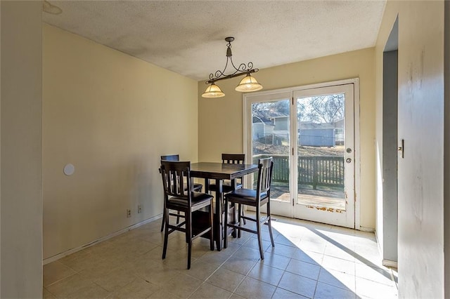 tiled dining area featuring a textured ceiling and baseboards