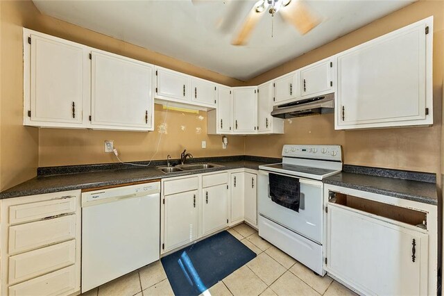 kitchen featuring dark countertops, under cabinet range hood, light tile patterned flooring, white appliances, and a sink