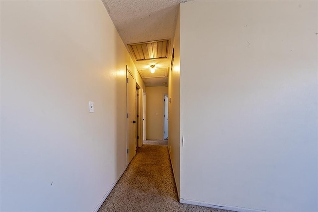 corridor featuring light carpet and a textured ceiling