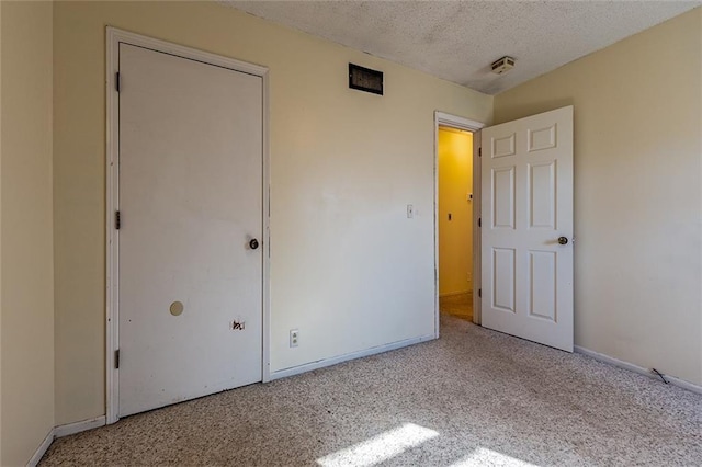 unfurnished bedroom with carpet, baseboards, and a textured ceiling