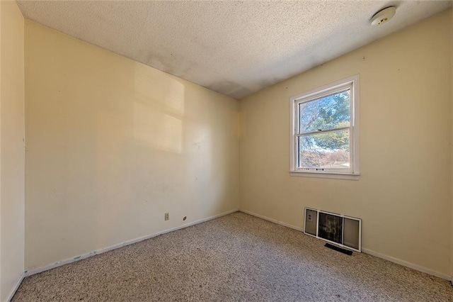 empty room with carpet flooring, a textured ceiling, and baseboards