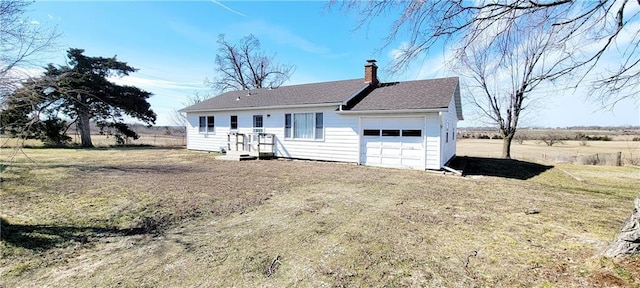 view of front facade with a garage, a front yard, driveway, and a chimney