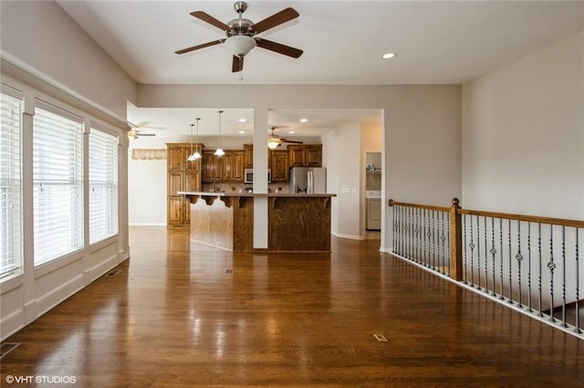 unfurnished living room featuring a ceiling fan, baseboards, washer / dryer, recessed lighting, and dark wood-style flooring