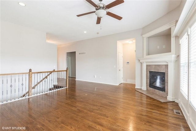 unfurnished living room with visible vents, ceiling fan, recessed lighting, a tile fireplace, and wood finished floors
