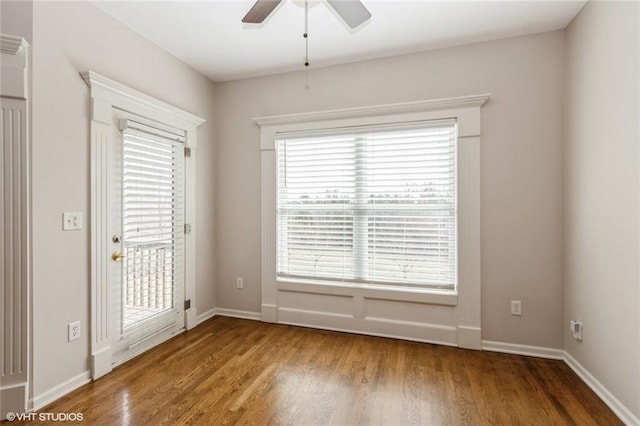 unfurnished room with baseboards, wood finished floors, and a ceiling fan