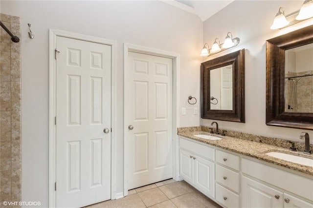 full bathroom featuring tile patterned flooring, double vanity, a tile shower, and a sink