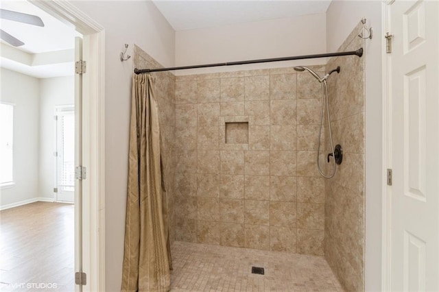 full bath with tiled shower, ceiling fan, and wood finished floors