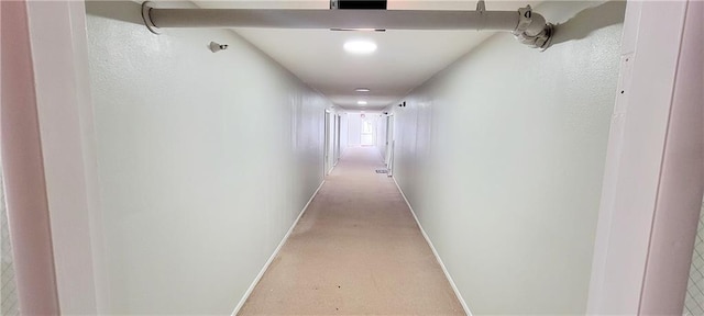 hallway featuring light carpet and baseboards