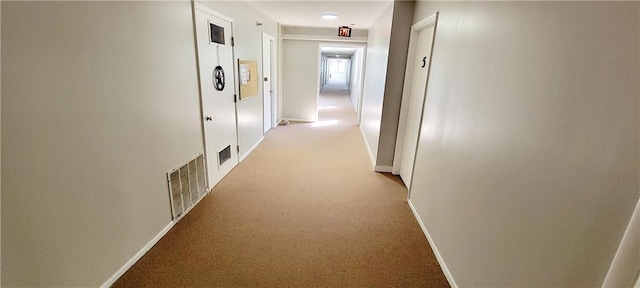 corridor with visible vents, light carpet, and baseboards