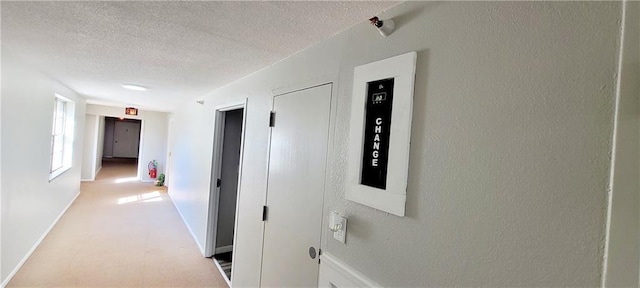 corridor with a textured ceiling, a textured wall, and baseboards