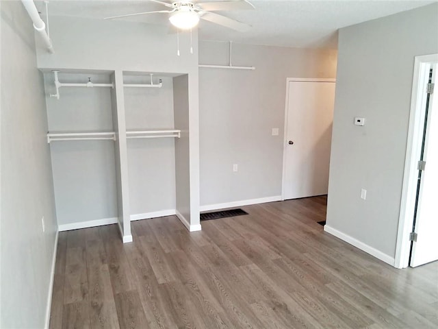 unfurnished bedroom with multiple closets, ceiling fan, baseboards, and wood finished floors