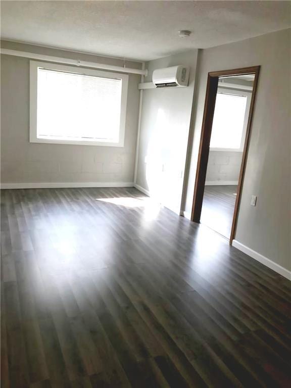 spare room with dark wood-style floors, a wall mounted air conditioner, and baseboards