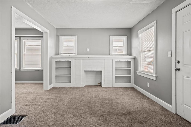 unfurnished living room featuring baseboards, a fireplace, a textured ceiling, and carpet