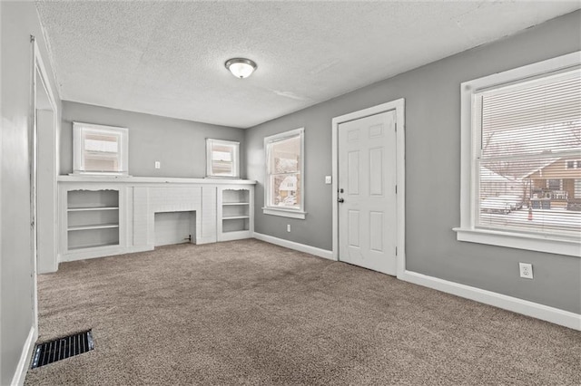 unfurnished living room featuring carpet flooring, visible vents, and a wealth of natural light