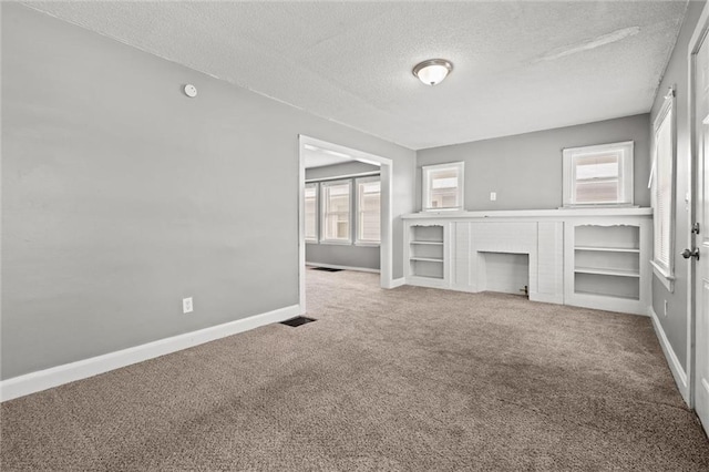 unfurnished living room with visible vents, a textured ceiling, carpet, a fireplace, and baseboards