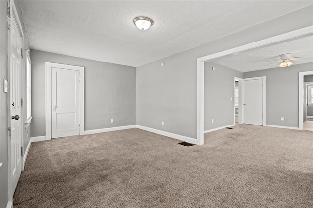 carpeted spare room featuring ceiling fan, baseboards, and a textured ceiling