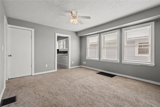 unfurnished bedroom featuring visible vents, carpet floors, a textured ceiling, and baseboards