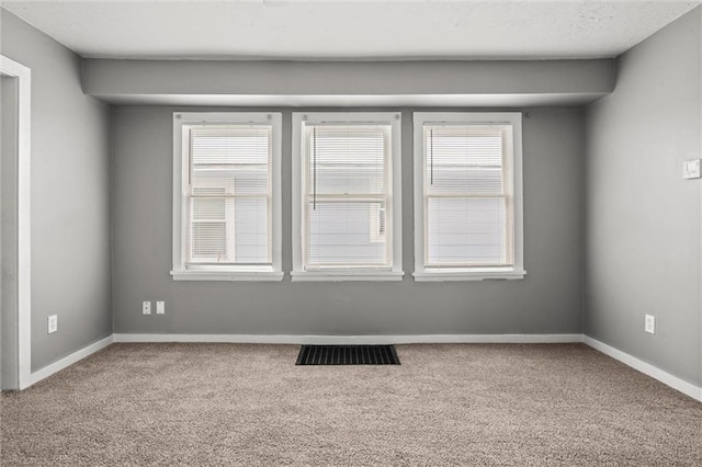 carpeted spare room with visible vents and baseboards