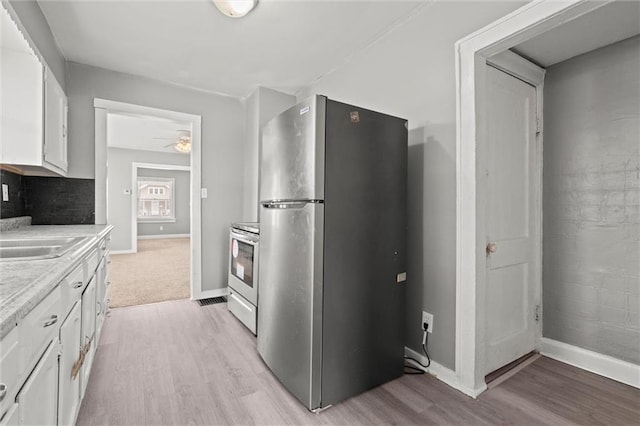 kitchen featuring light countertops, white cabinets, light wood-type flooring, and stainless steel appliances