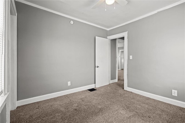 carpeted spare room with visible vents, baseboards, ornamental molding, and a ceiling fan