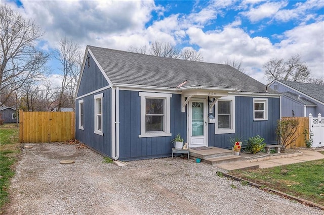 bungalow-style home featuring a shingled roof and fence