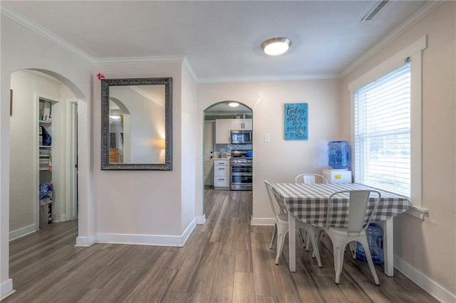 dining space featuring crown molding, baseboards, and wood finished floors