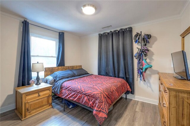 bedroom featuring light wood-style floors, baseboards, and ornamental molding