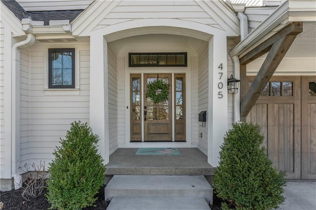 view of exterior entry featuring a shingled roof