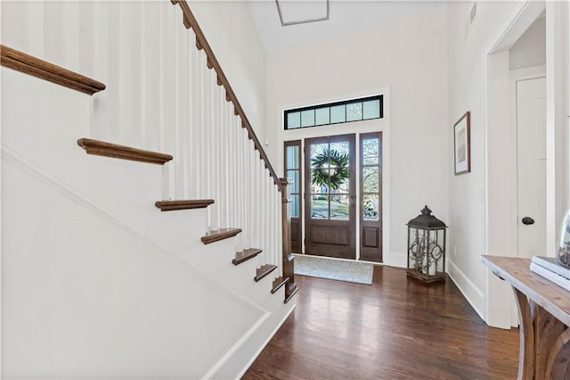 entryway with a towering ceiling, baseboards, wood finished floors, and stairs