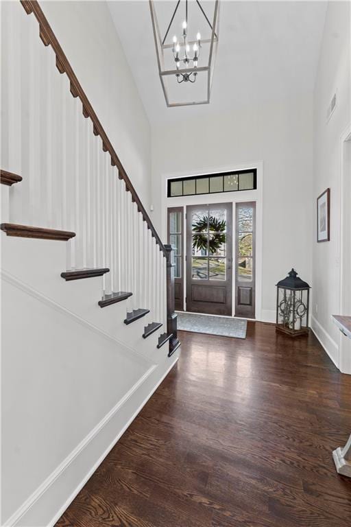 entrance foyer featuring a notable chandelier, wood finished floors, stairway, baseboards, and a towering ceiling