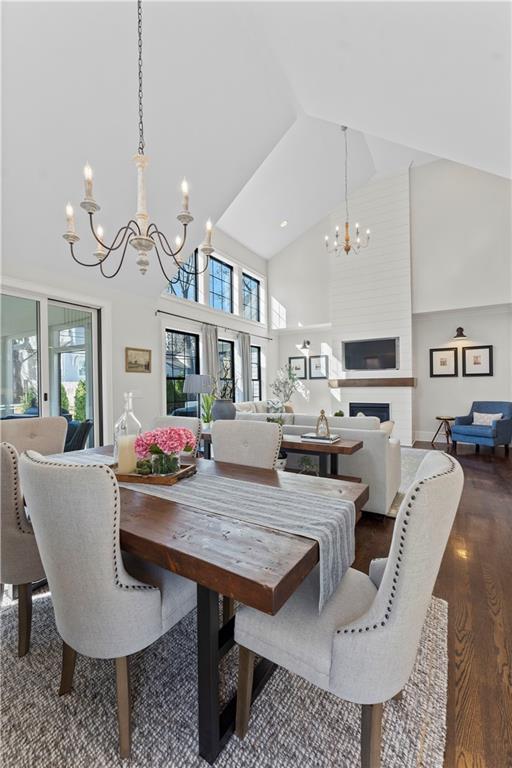 dining space with dark wood-style floors, a healthy amount of sunlight, high vaulted ceiling, and an inviting chandelier