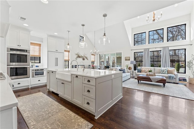 kitchen with an inviting chandelier, double oven, visible vents, and a sink