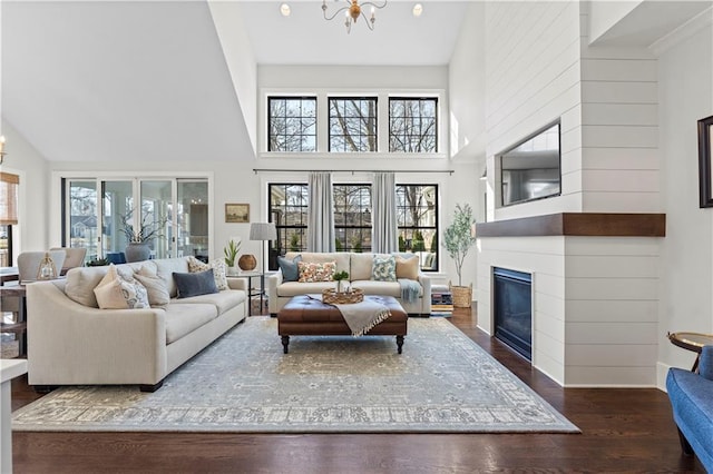 living area with a large fireplace, a notable chandelier, wood finished floors, and high vaulted ceiling