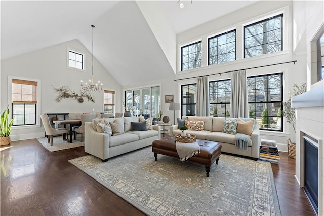 living area featuring an inviting chandelier, a fireplace, dark wood-style flooring, and a healthy amount of sunlight