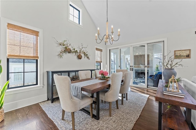 dining room featuring baseboards, a notable chandelier, wood finished floors, and high vaulted ceiling