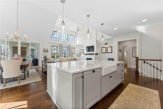 kitchen featuring dark wood-type flooring, open floor plan, light countertops, hanging light fixtures, and a sink