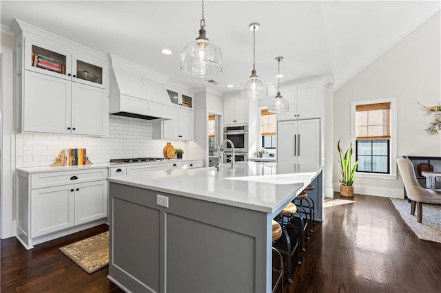 kitchen with premium range hood, light countertops, a kitchen breakfast bar, stainless steel appliances, and a sink