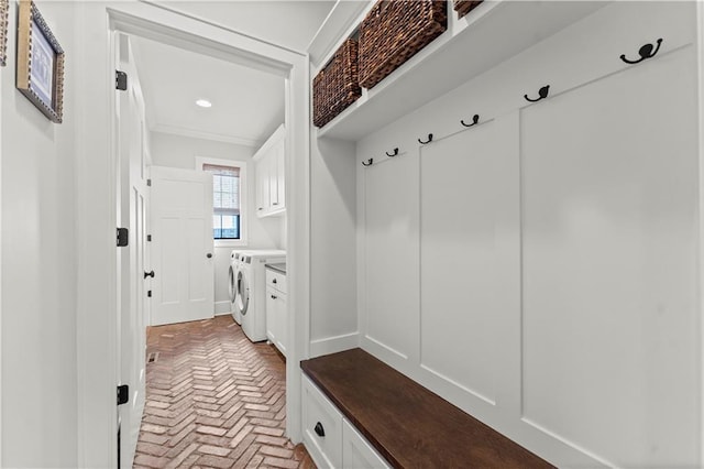 mudroom featuring brick floor, crown molding, and washer and clothes dryer