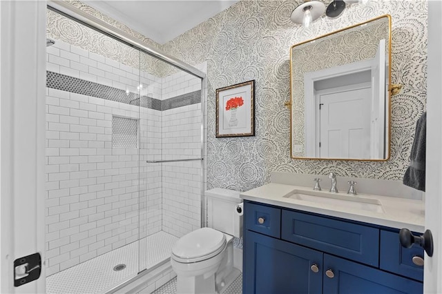 bathroom with wallpapered walls, toilet, vanity, and a stall shower