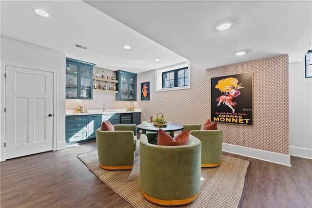 interior space with baseboards, visible vents, wallpapered walls, wet bar, and dark wood-style flooring